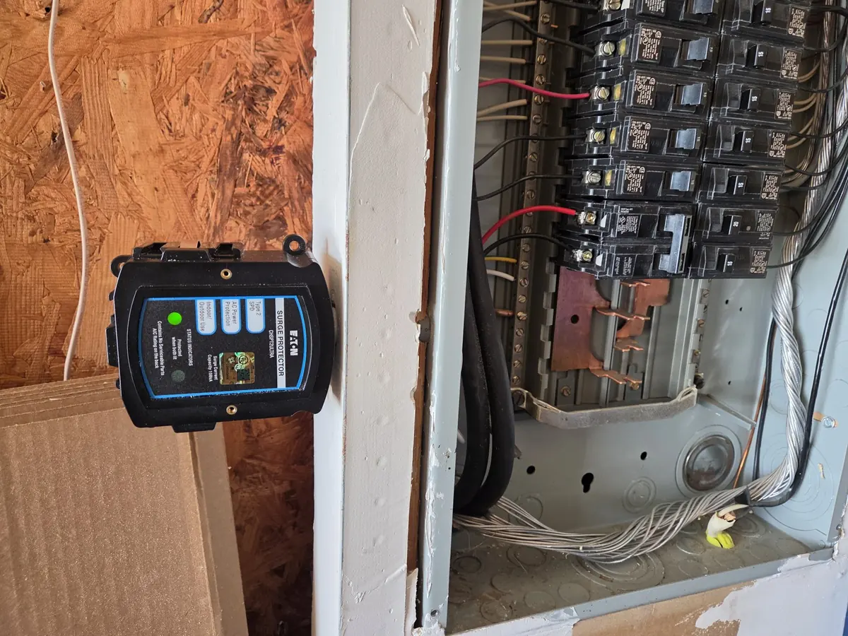 Whole-house surge protector mounted next to an open electrical panel