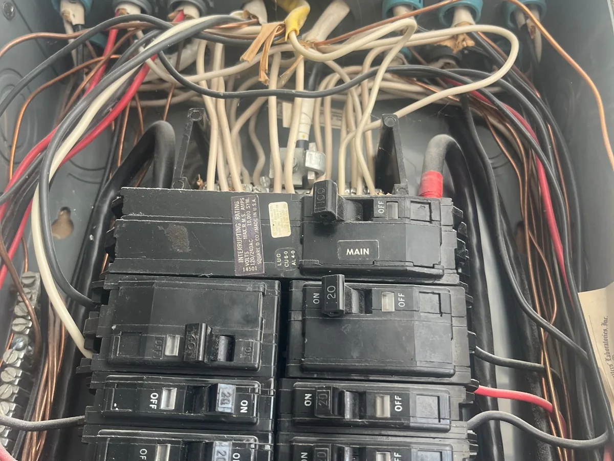 Old breaker panel with crowded, tangled wiring around the breakers