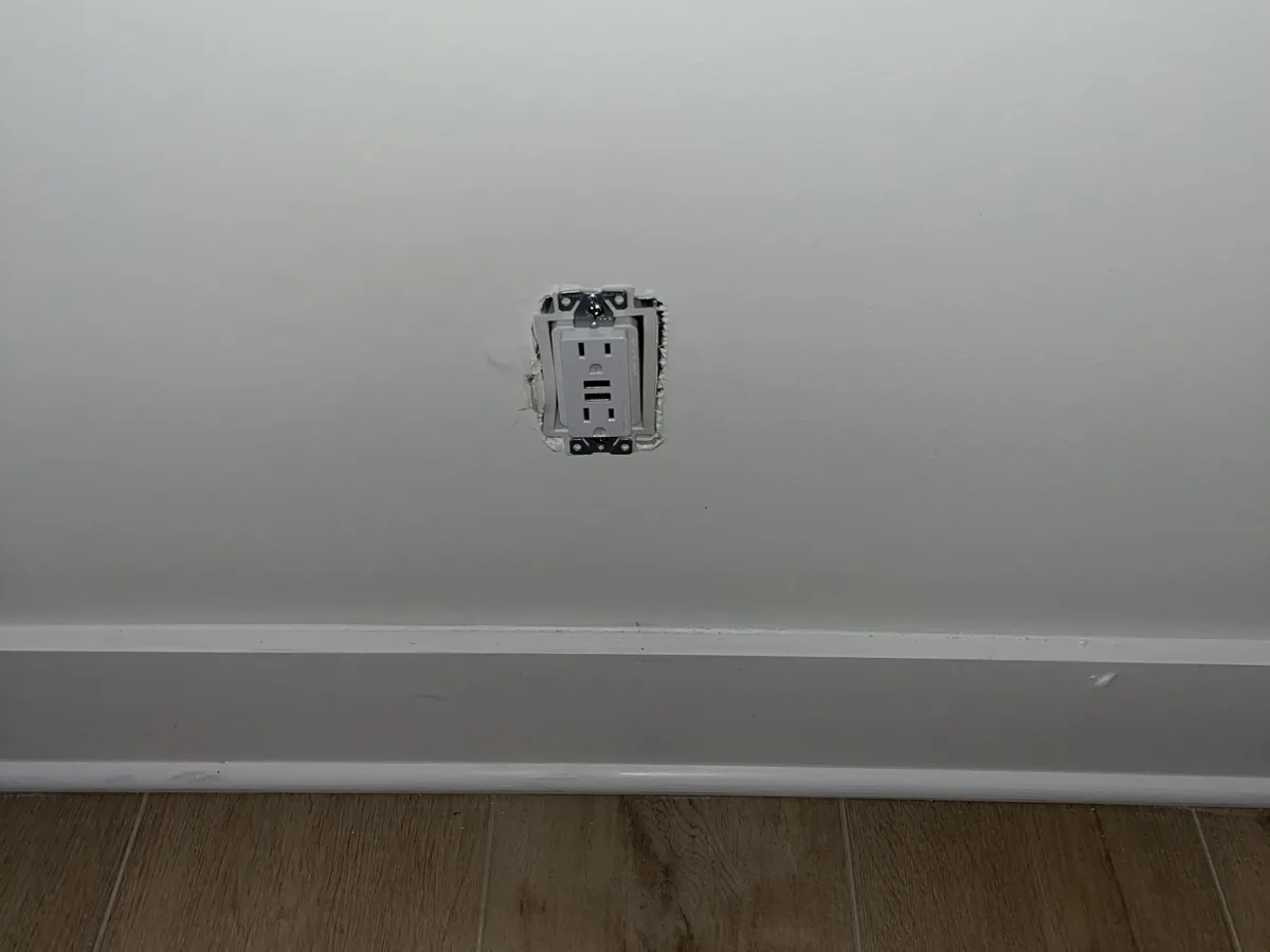 New outlet installed on a living room wall above the baseboard
