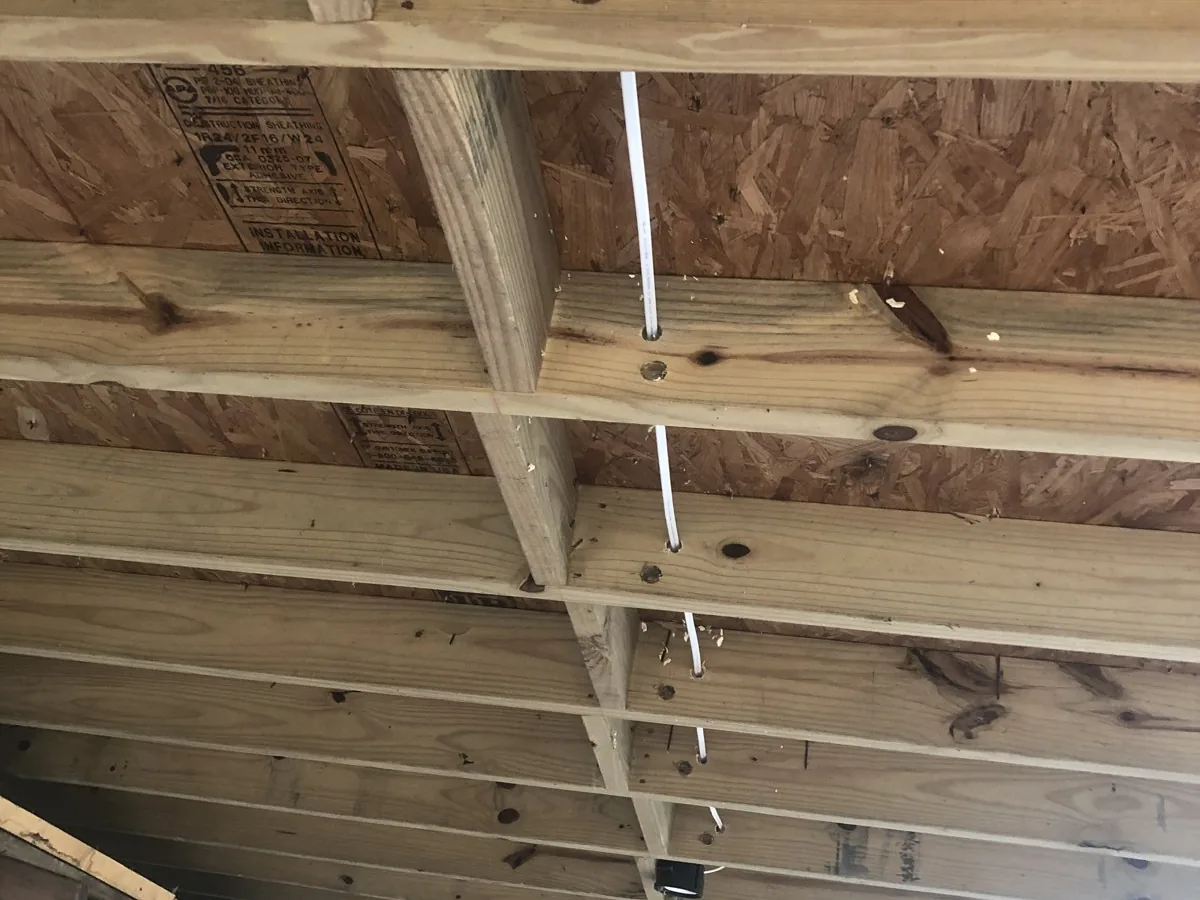New electrical cable run through open ceiling joists