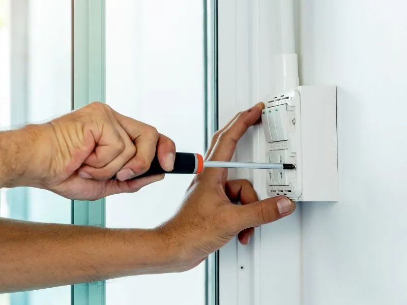 Electrician installing a wall switch with a screwdriver