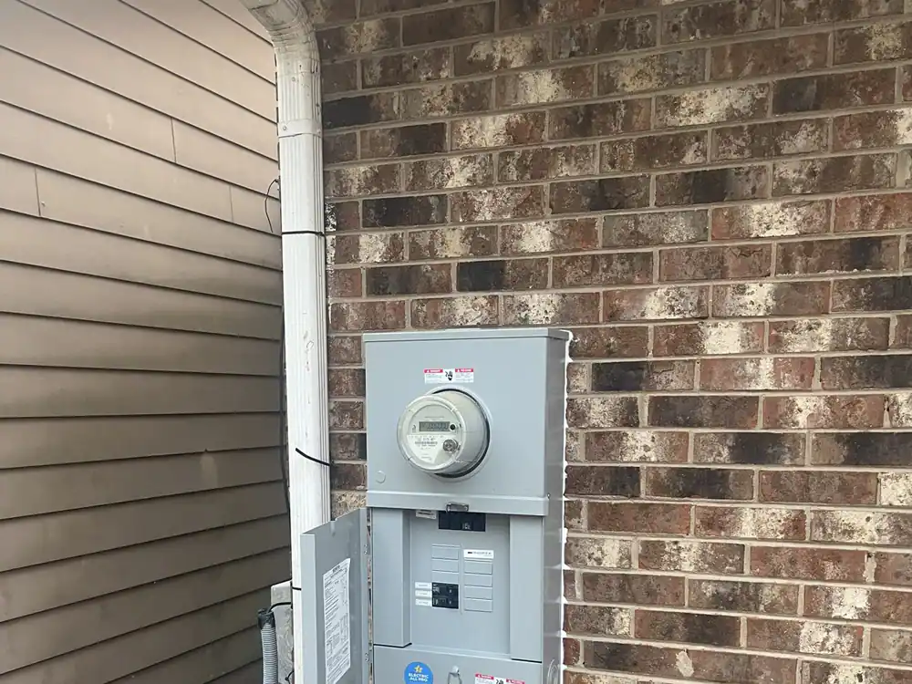 Electric meter and breaker panel mounted on an exterior brick wall, with the cover open, in Boylan Heights, Raleigh