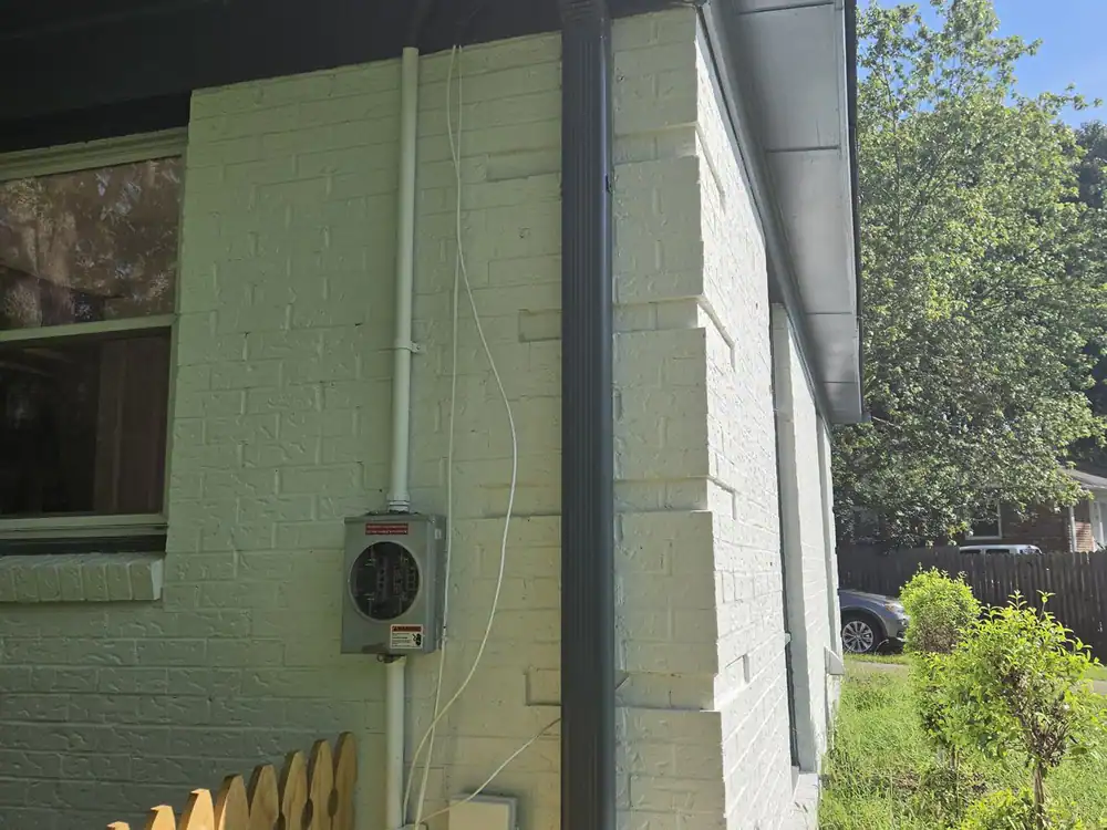 Utility meter and wiring mounted on the white brick wall of a house in MacGregor Downs, Cary