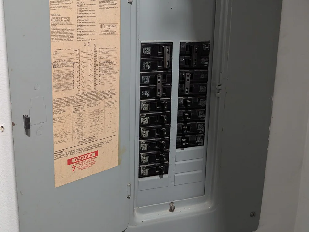 Open electrical panel mounted on an interior wall, with rows of breakers and a label inside the door, in Hayes Barton, Raleigh