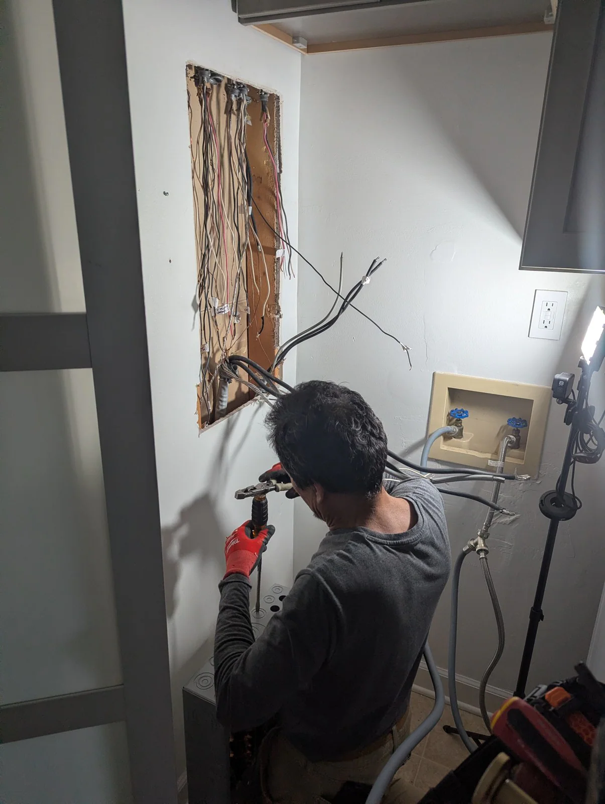 Electrician working on exposed wiring inside an opening in a wall, in Hayes Barton, Raleigh