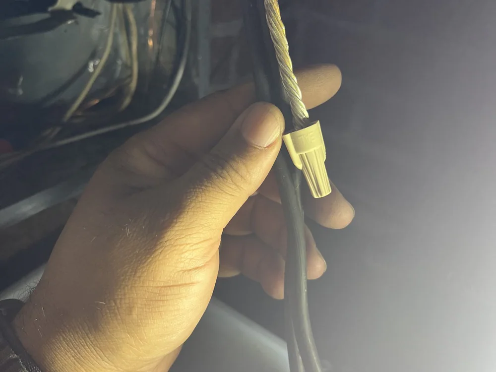 An electrician's hand holding a wire fitted with a connector during wiring work in Trinity Park, Durham