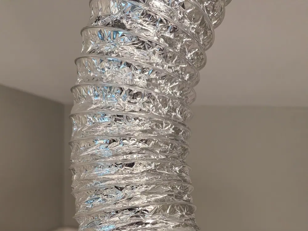 Flexible metal duct connected to a black mounting base in a bathroom in Raleigh