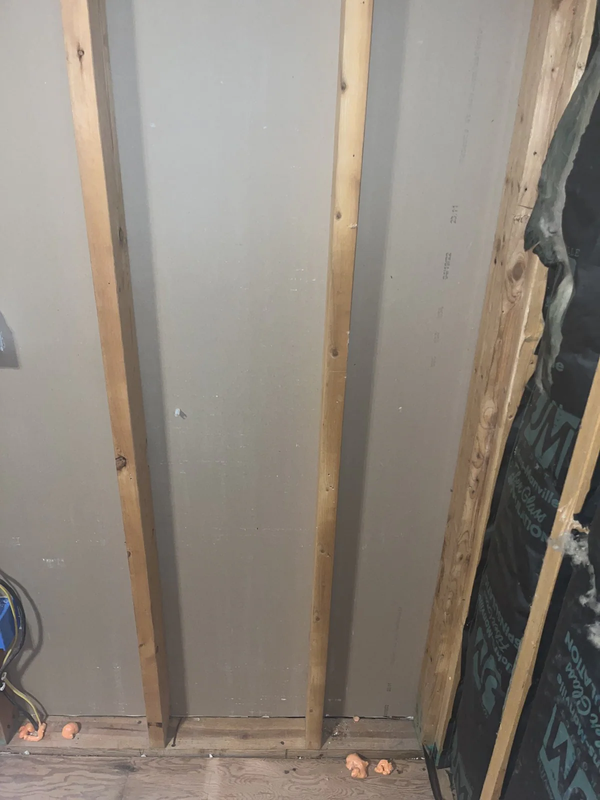 Drywall fastened to wooden framing beside an open section where insulation and electrical wiring remain visible in Mordecai, Raleigh
