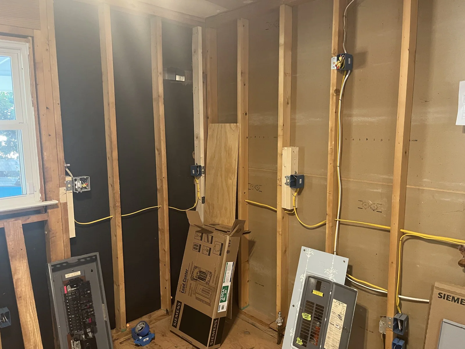 Electrical panel and wiring in an unfinished room with exposed wooden framing in Mordecai, Raleigh