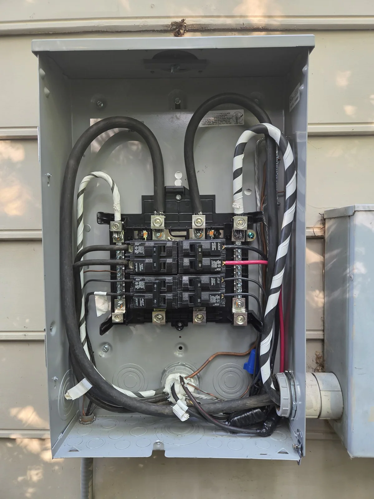 An open electrical panel with wires and breakers exposed while work is in progress, in Oakwood, Raleigh