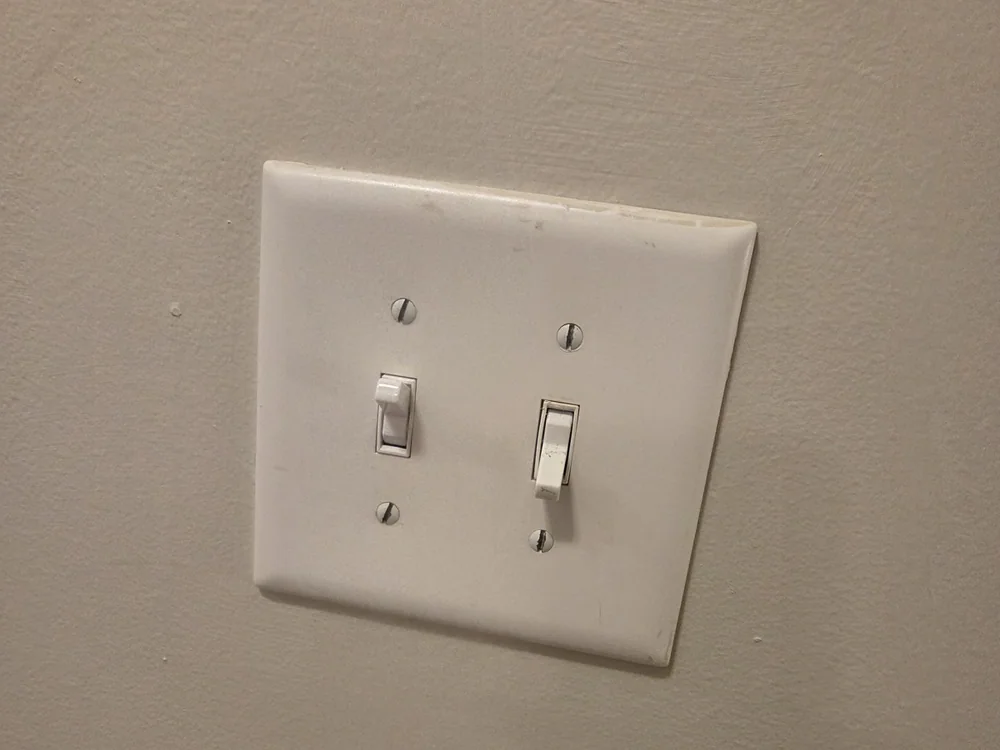 A white double light switch plate mounted on a beige wall at the second-floor switch location in Hayes Barton, Raleigh