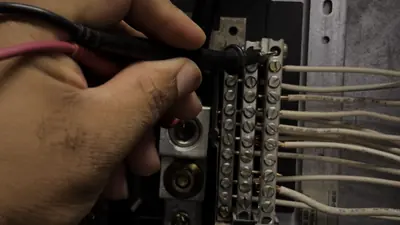 Electrician testing a breaker panel with a multimeter