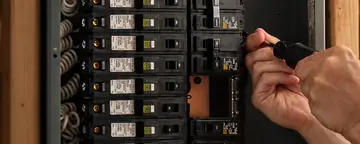 Electrician working on breakers in an open electrical panel