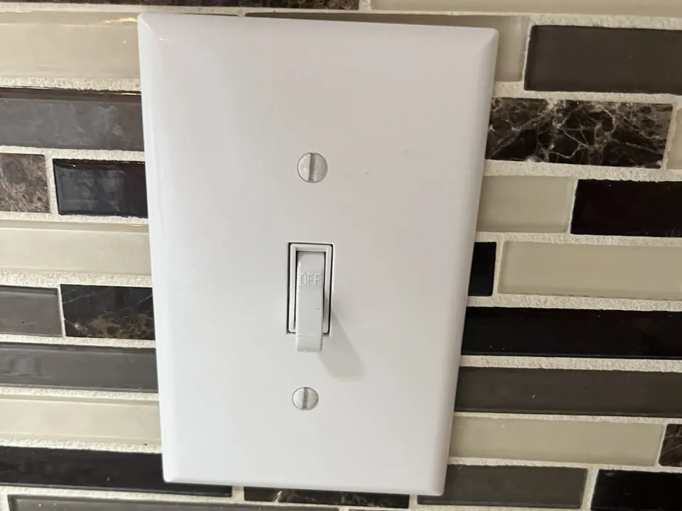 Light switch on a tiled backsplash wall
