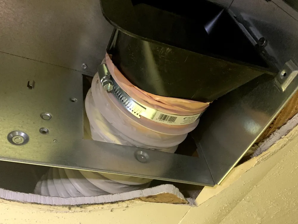 Exhaust fan housing with its flexible duct connected above the ceiling