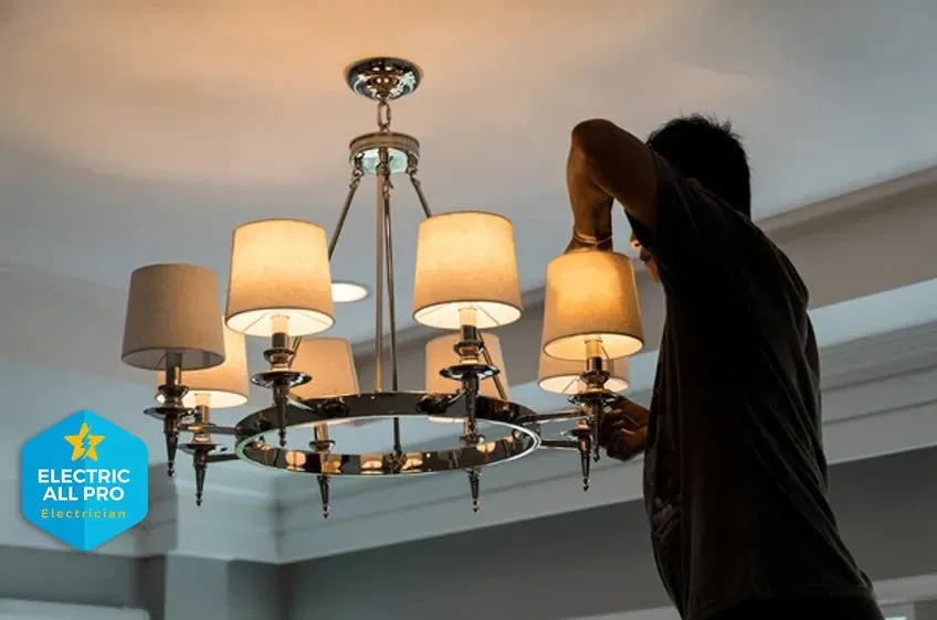 Electrician installing a multi-arm chandelier in a Raleigh home