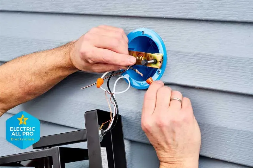 Electrician wiring an exterior light fixture box on a Raleigh home