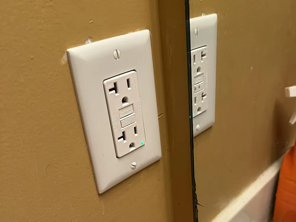 New GFCI outlet beside a bathroom mirror