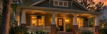 Craftsman bungalow with a deep front porch on a tree-lined street at dusk