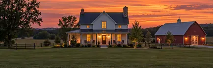 Country home on open acreage with a detached barn at dusk